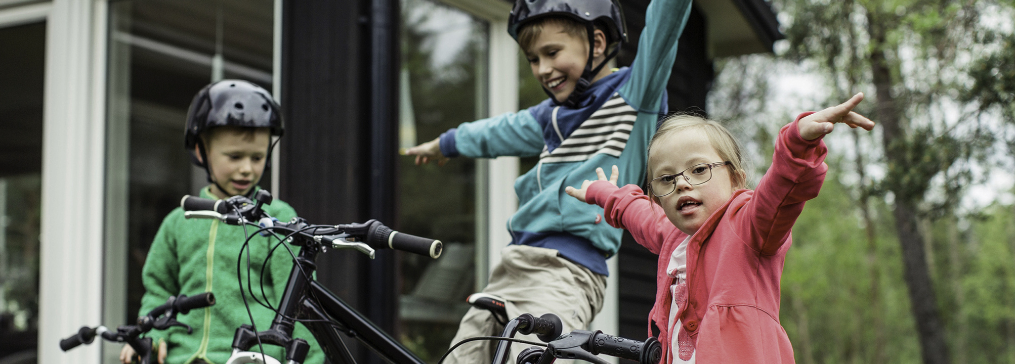 Tre barn sitter på sina cyklar och ser glada ut.