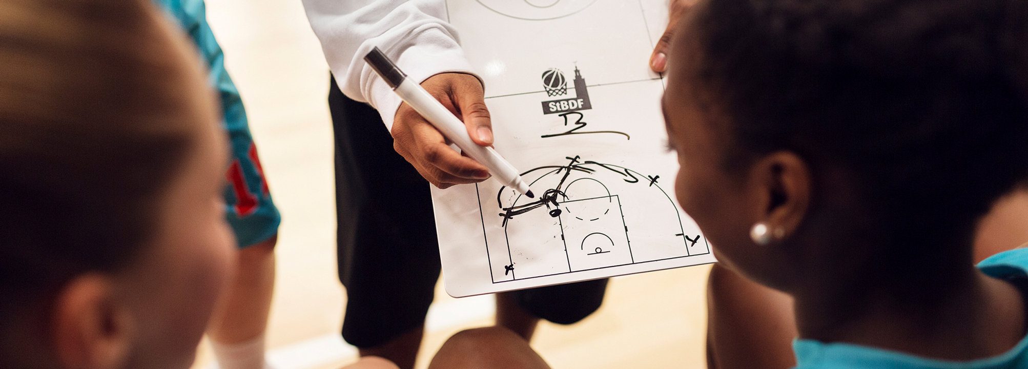 Basketspelare får instruktioner från sin tränare ritat på en tavla.